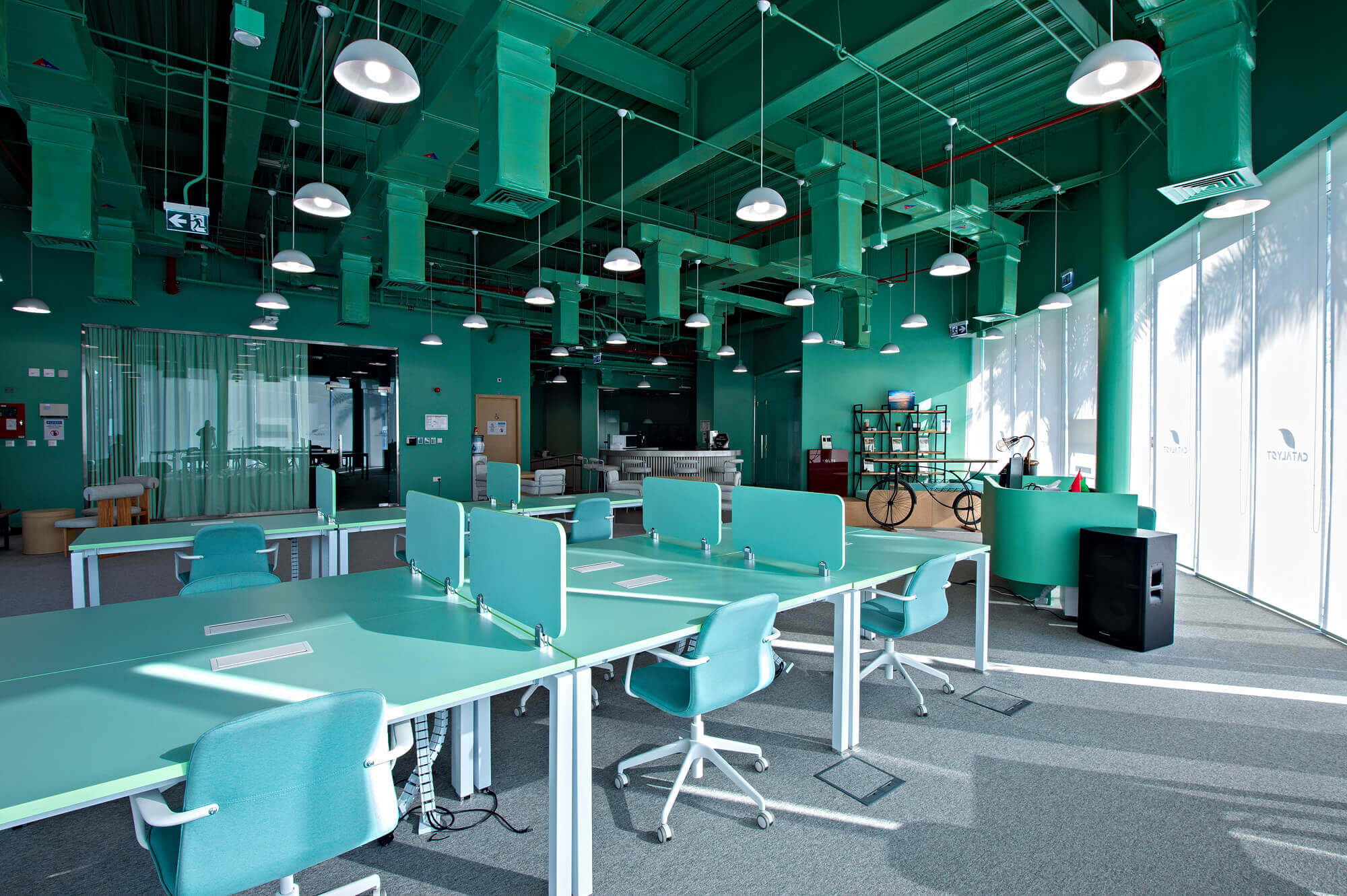 Modern open-plan office with turquoise color scheme and pendant lighting
