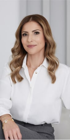 Portrait of female professional with wavy hair wearing white blouse in modern office