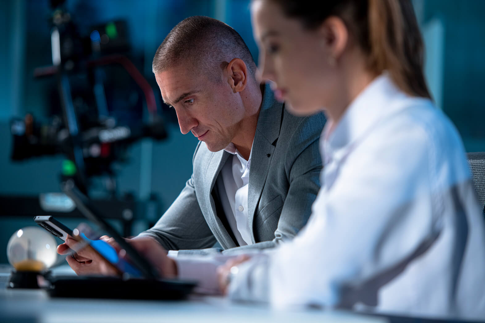 Two professionals in a modern office collaborating, analyzing data on a smartphone