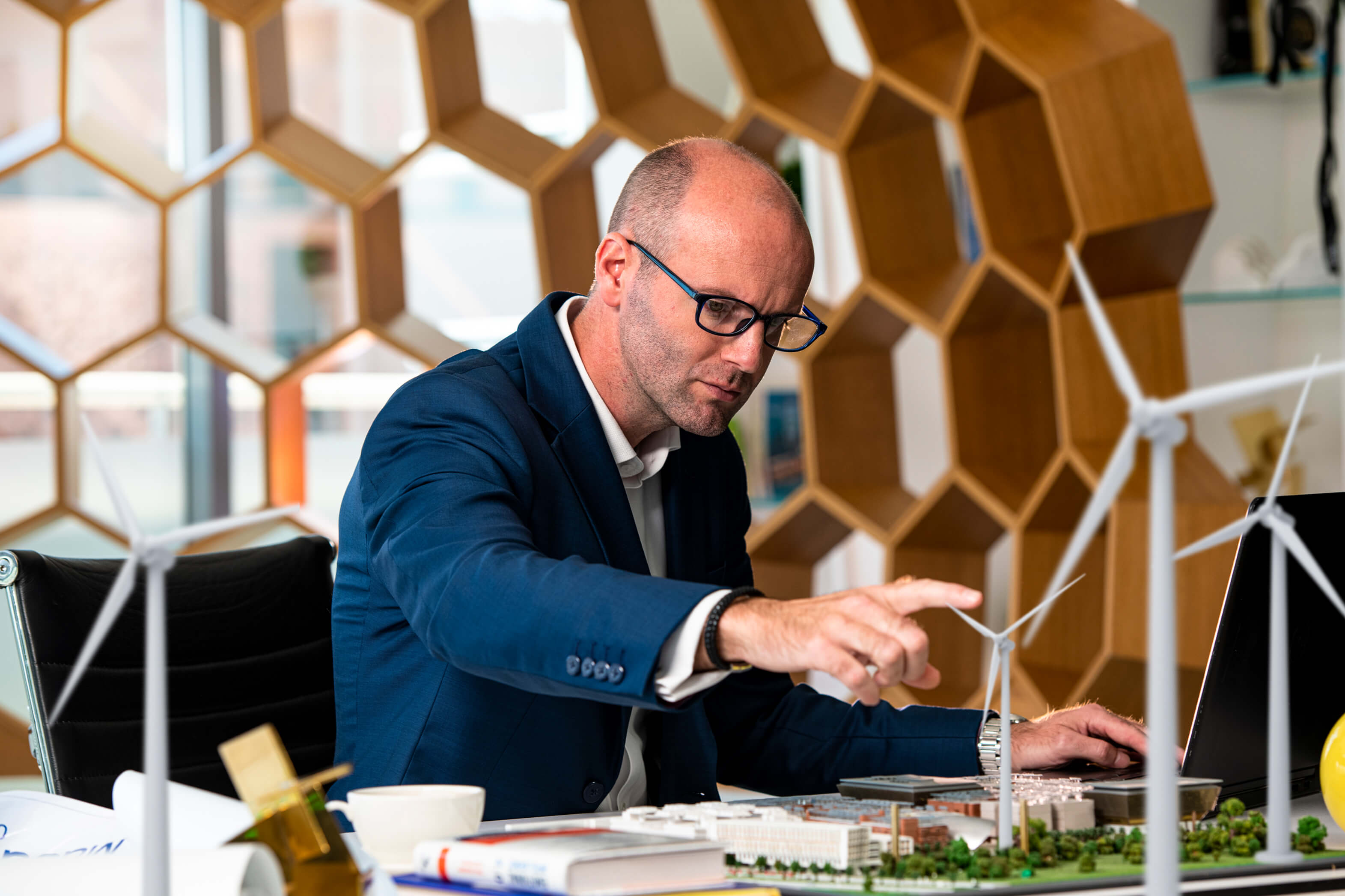 Business professional examining scale model of building development at desk
